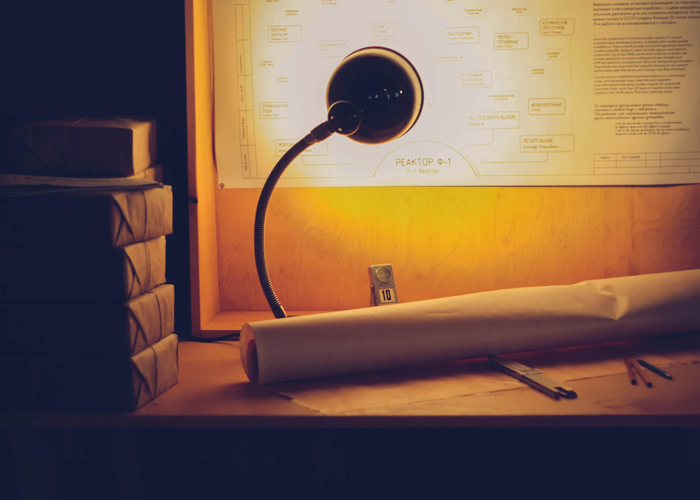 A desk lamp illuminating paper plans and notes
